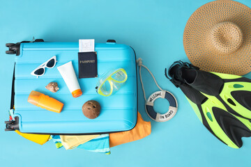 Suitcase with beach accessories, cosmetics and passport on color background