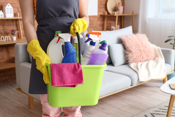 Woman holding bucket with detergents at home