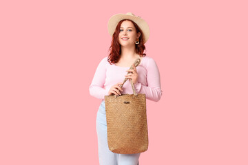 Beautiful young happy woman with stylish wicker bag on pink background