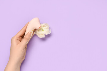Female hand with vibrator and flower on purple background. Sex education - obrazy, fototapety, plakaty