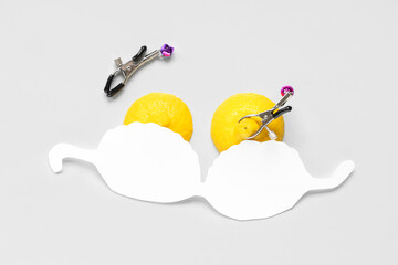 Fresh lemons with nipple clamps on white background. Sex education
