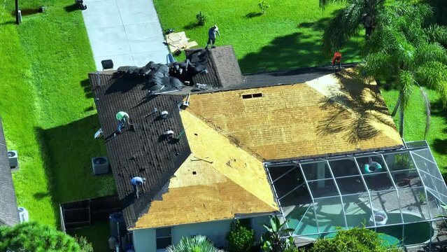 Workers changing old asphalt shingles to new on private house rooftop. Roof repair on Florida home. Real estate development concept