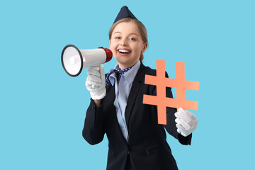 Young stewardess with hashtag sign and megaphone on blue background