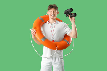Male lifeguard with binoculars and ring buoy on green background