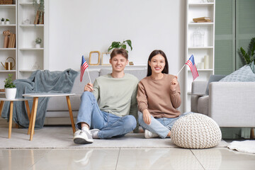 Young couple with flags of USA sitting on floor at home