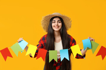 Beautiful young happy woman with flags on yellow background. Festa Junina (June Festival)...