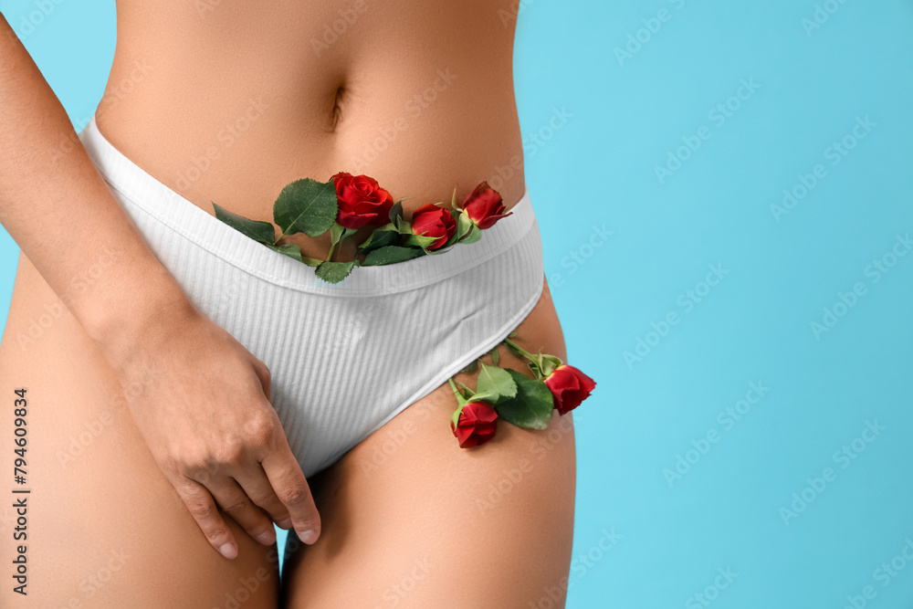 Wall mural beautiful young woman in panties with rose flowers on blue background, closeup