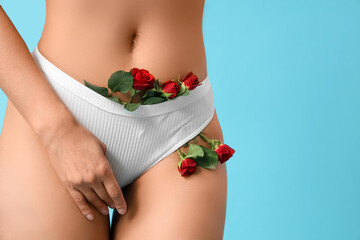 Beautiful young woman in panties with rose flowers on blue background, closeup - obrazy, fototapety, plakaty