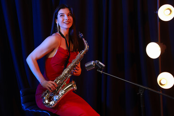 Beautiful woman with saxophone performing on stage