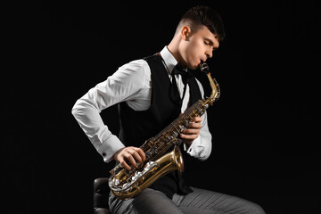 Male artist playing saxophone on black background
