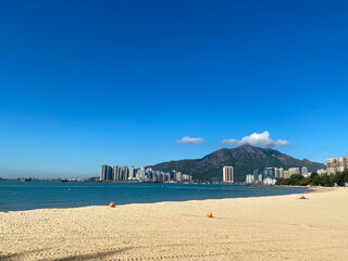 Serene Beachfront with Distant Cityscape and Mountain View