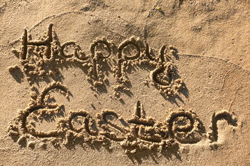 Text HAPPY EASTER written on sand on sea beach