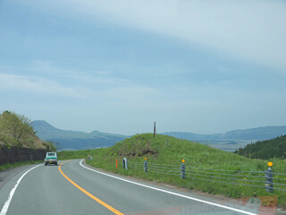 Travelling on Kyushu, driving to distant Mount Aso famous volcano caldera contour on lonely road...