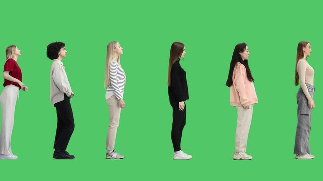 A full-length group of people on a green background are standing in line