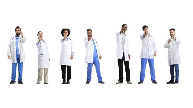A group of doctors, in full height, on a white background, points forward