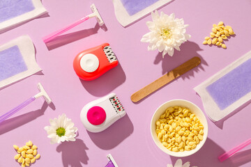 Modern epilators with razors, wax and flowers on lilac background