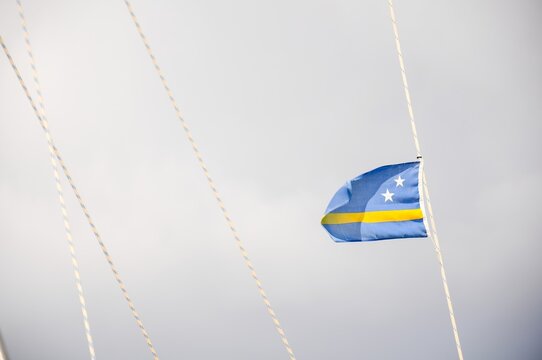 A blue and yellow flag with stars is hanging from a rope Aruba waving wind