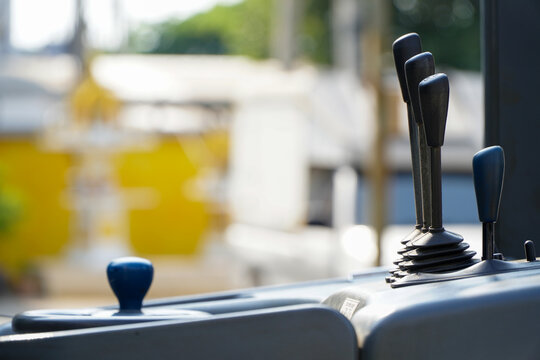 Asian male worker drives a forklift in an industrial factory. Gearshift handle lever of the forklift vehicle control panel dashboard. Concept of industrial and industrial workers