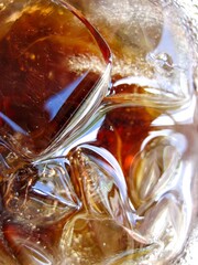 A glass of soda with ice cubes in it