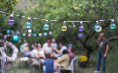 Multi-colored lanterns on trees at a friendly summer garden party, abstract background