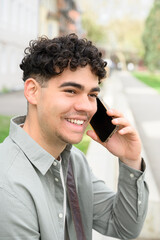young happy man making a phone call outdoors on street