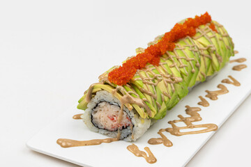 A plate with California roll featuring avocado topped with sauce, plated on a white background