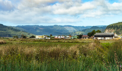View of a village town with green grass as foreground and hills as background in Cobquecura, south...