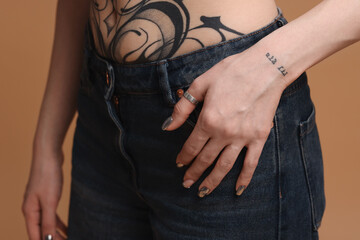 Woman with cool tattoos on beige background, closeup