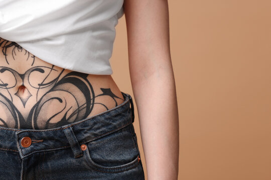 Woman with cool tattoos on beige background, closeup. Space for text