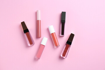 Different lip glosses on pink background, flat lay - obrazy, fototapety, plakaty