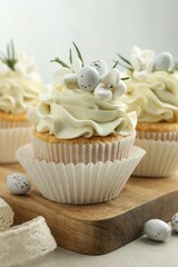 Tasty Easter cupcakes with vanilla cream on gray table, closeup