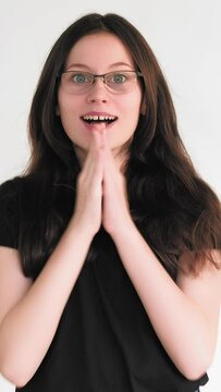 Vertical video. Excited winner. Victory surprise. Astonished joyful happy woman in glasses celebrating success clapping hands isolated on white.