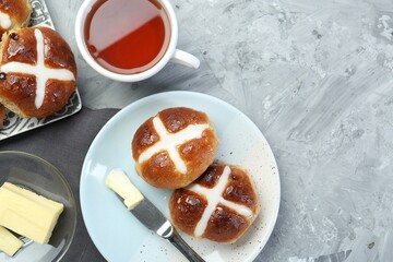 Tasty hot cross buns served on gray textured table, flat lay. Space for text