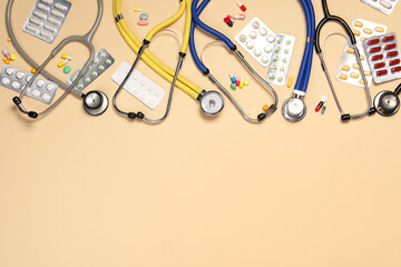 Stethoscopes and pills on beige background, flat lay. Space for text