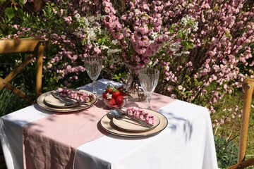 Stylish table setting with beautiful spring flowers in garden