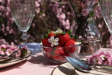 Stylish table setting with beautiful spring flowers in garden, closeup