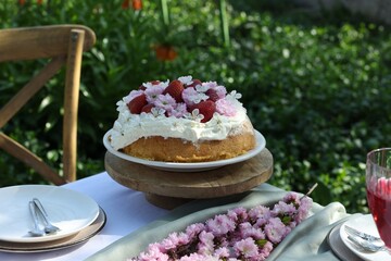Beautiful spring flowers and delicious cake on table in garden