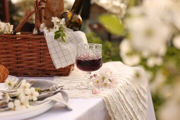 Stylish table setting with beautiful spring flowers and wine in garden