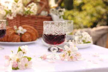 Stylish table setting with beautiful spring flowers, wine and croissants in garden