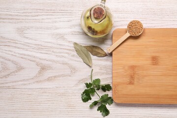 Cutting board, spices and oil on light wooden table, flat lay. Space for text