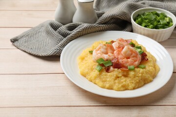Plate with fresh tasty shrimps, bacon, grits and green onion on light wooden table, space for text