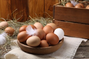 Fresh chicken eggs and dried hay on wooden table