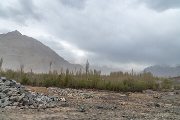 Landscape of Leh, Ladakh. Landscape view of rocky land and green trees surrounded by Himalayas and Dramatic clouds.  