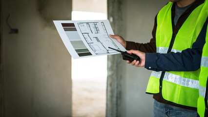 Two engineer hold radio communication and checking about blueprint of building in construction site