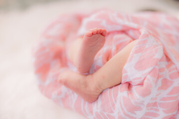 Sweet baby legs and feet from a newborn baby girl wrapped in a pink blanket.