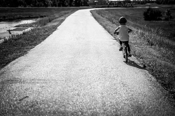 Caucasian boy wearing a helmet while riding a bike down a paved park path 