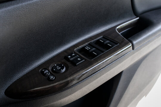 mirror adjustment buttons and power window buttons on driver's door of modern car, shallow depth of field