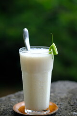 soursop juice in a clear glass. fresh drink from tropical fruit. stone table.
