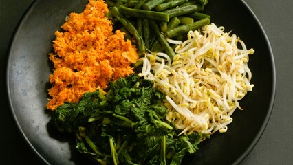 Urap, Indonesia traditional food served on plate with black background. Salad dish consist of...