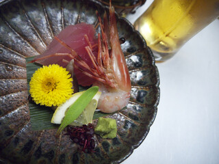 Gourmet shrimp and amberjack sashimi on ceramic plate decorated with yellow Chrysanthemum flower...